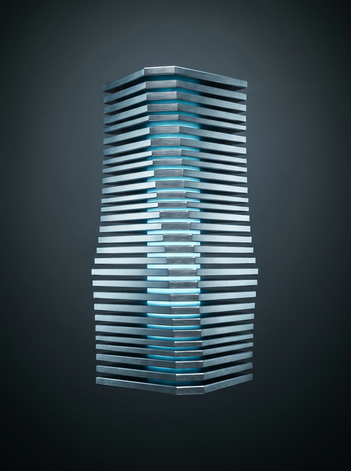 A stack of machined steel plates in precise alignment, lit from between the seams.